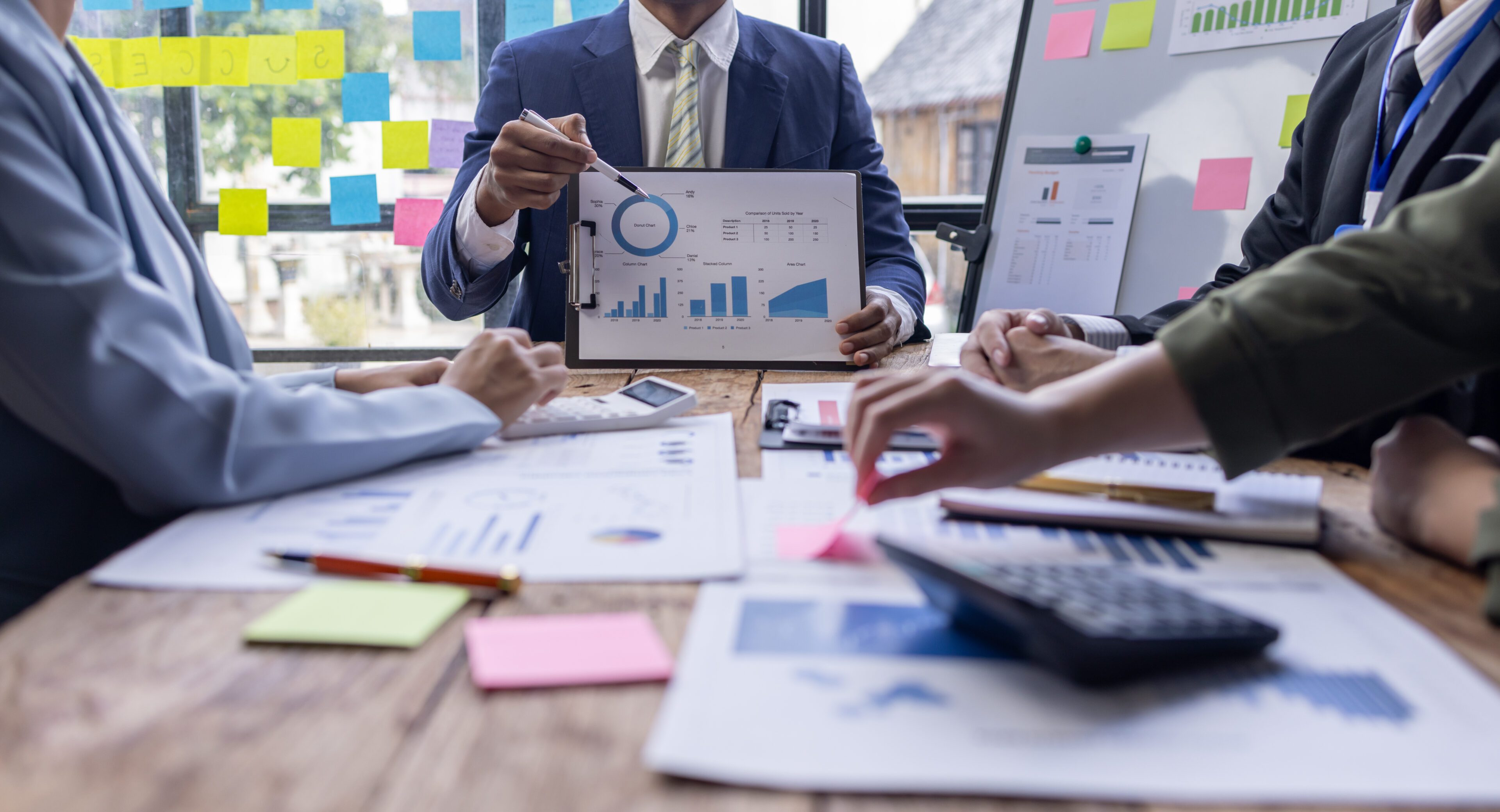 Group of confident business people point to graphs and charts to analyze market data, balance sheet, account, net profit to plan new sales strategies to increase production capacity. Business team reviewing sales charts.